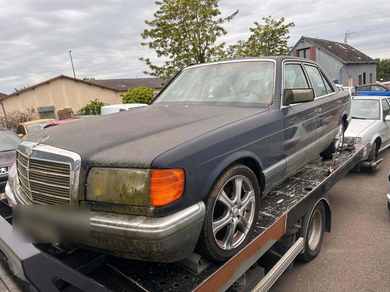Berline Mercedes hors d'usage chargée sur la dépanneuse plateau