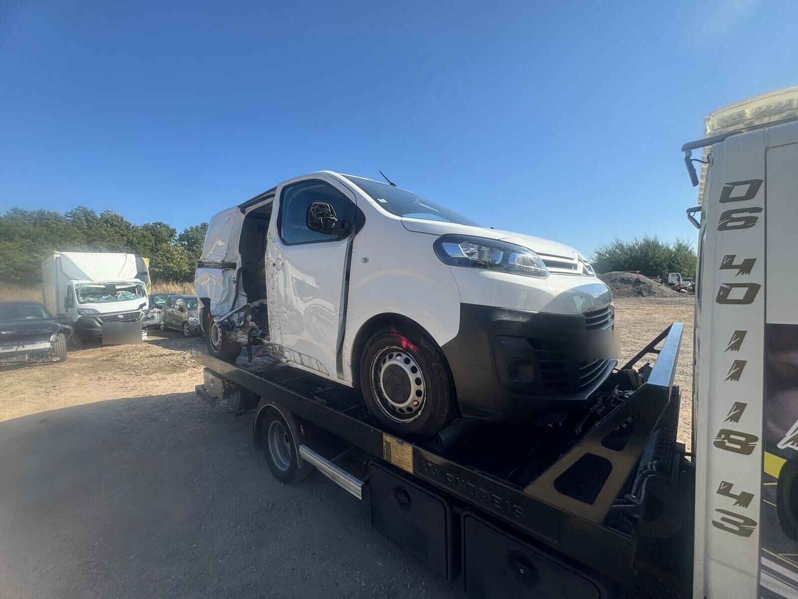Utilitaire blanc accidenté arrimé sur le plateau de la dépanneuse